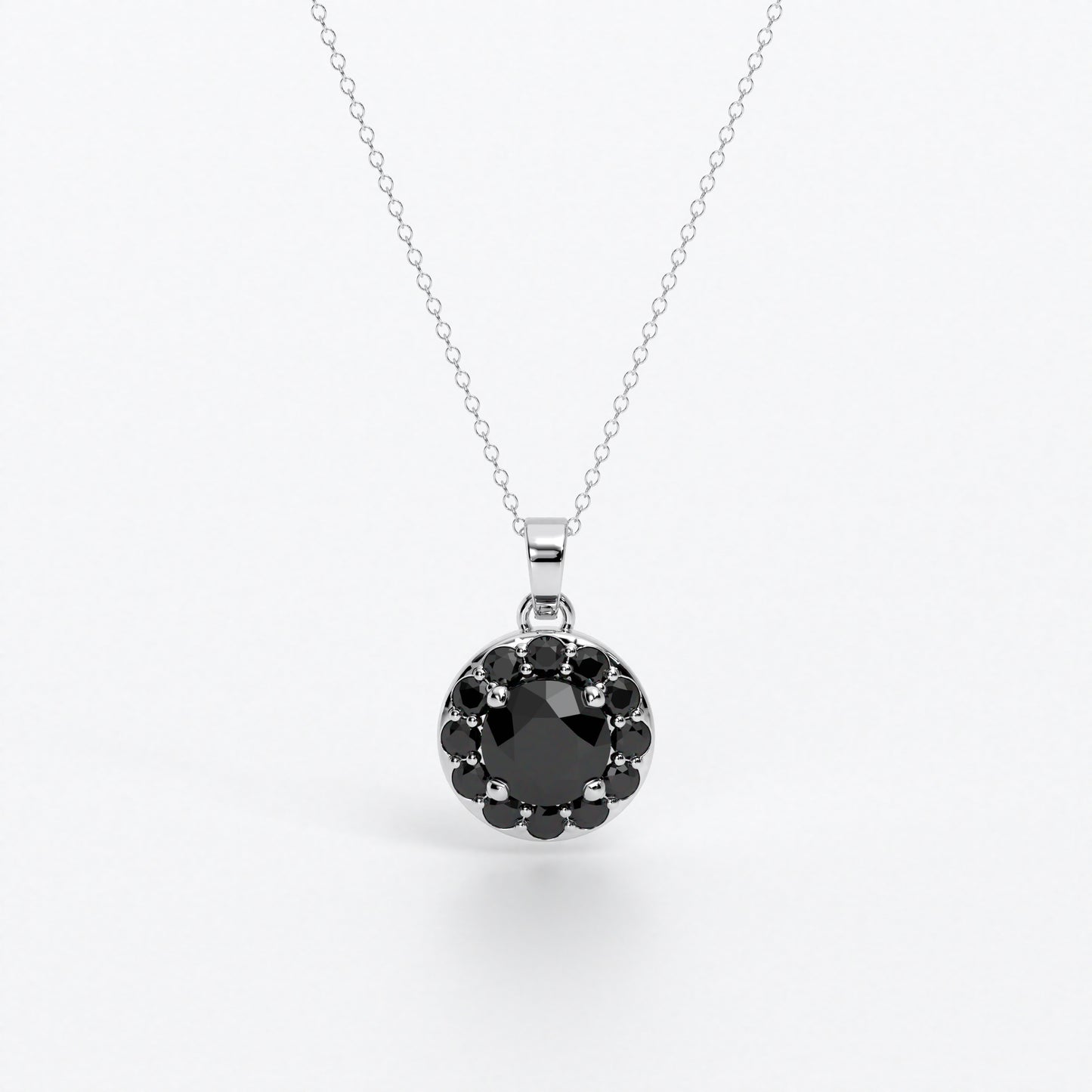 Colgante de oro de 18k con diamante negro central en talla brillante, rodeada por un halo de diamantes negros, con un total de 1,1cts