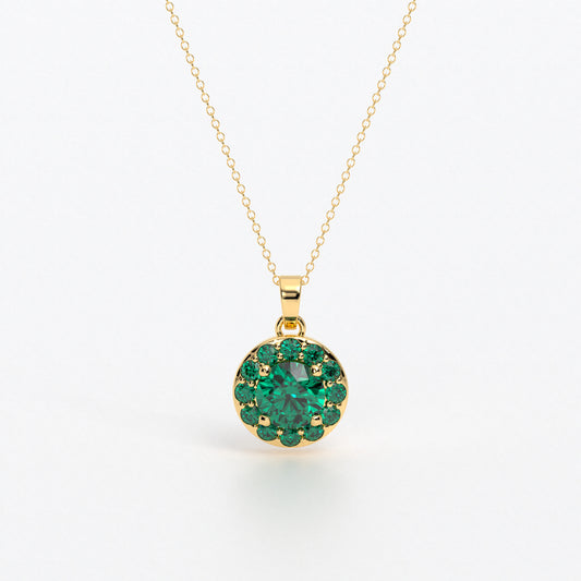 Colgante de oro de 18k con esmeralda central en talla brillante, rodeada por un halo de esmeraldas, con un total de 2cts