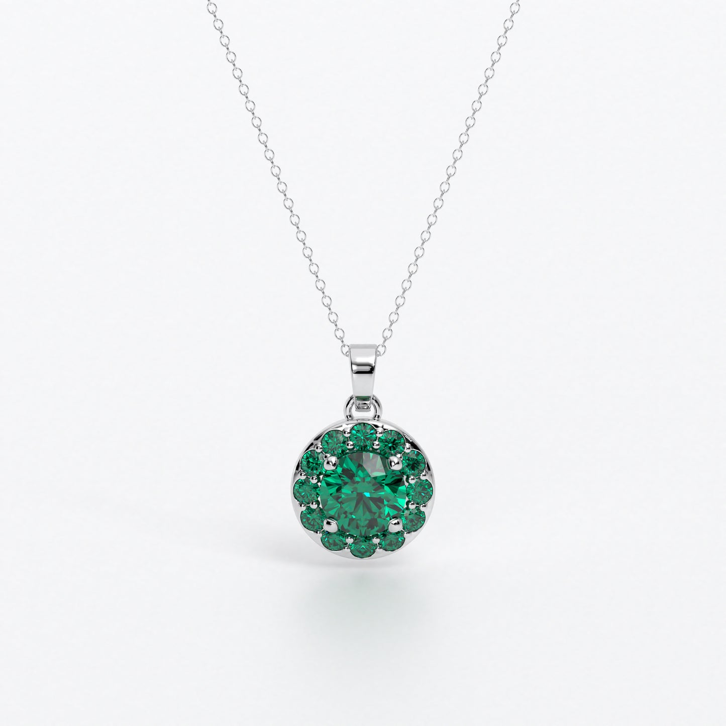 Colgante de oro de 18k con esmeralda central en talla brillante, rodeada por un halo de esmeraldas, con un total de 2cts